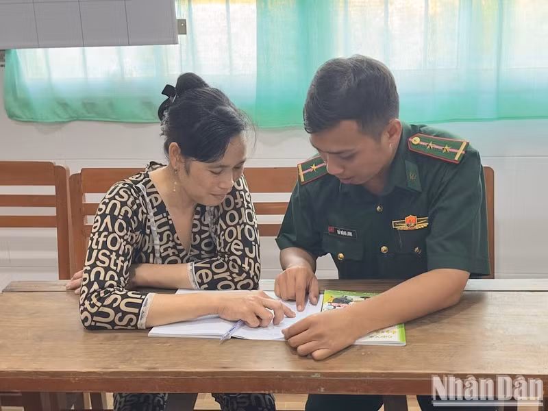 Lieutenant Ho Mong Long guides Duong Thuy Lieu in spelling.