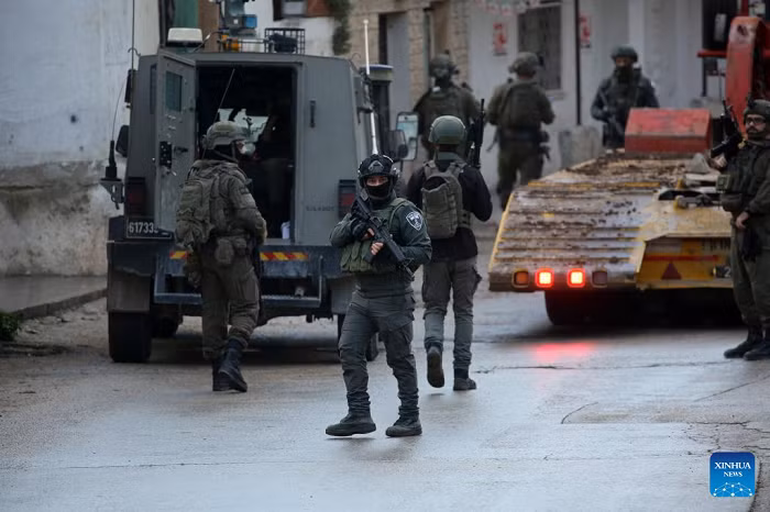 Members of Israeli forces stand guard as an Israeli bulldozer demolishes a house in the town of Bizzariya, northwest of Nablus in the West Bank, on Dec. 24, 2025. (Photo: Xinhua)