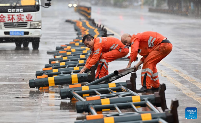 Staff members remove lane dividers pushed over by strong gusts in a street in Haikou, south China's Hainan Province, on Oct. 5, 2025. Typhoon Matmo, the 21st named storm of the 2025 Pacific typhoon season, is intensifying as it nears south China's coastal areas, leading to large-scale evacuations. The island province of Hainan has relocated over 197,000 people from high-risk areas as of Sunday noon, with a typhoon red alert remaining in effect. (Photo: Xinhua)