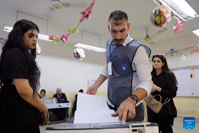A staff member assists voters to put their ballots into a ballot box at a polling center in Baghdad, Iraq, on Nov. 11, 2025. Iraqis began to vote in parliamentary elections on Tuesday morning for a new 329-member Council of Representatives. (Photo: Xinhua)