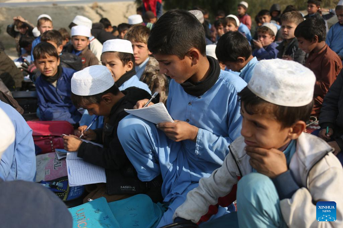 Students attend an outdoor class at a makeshift roadside school without proper shelters beside a highway junction in Nangarhar province, eastern Afghanistan, Dec. 16, 2025. (Photo: Xinhua)