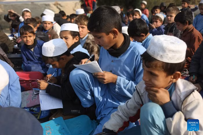 Students attend an outdoor class at a makeshift roadside school without proper shelters beside a highway junction in Nangarhar province, eastern Afghanistan, Dec. 16, 2025. (Photo: Xinhua)