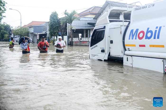 People wade through flood water after heavy rain in Benjeng village of Gresik Regency, East Java, Indonesia, June 10, 2025. ( Photo: Xinhua)