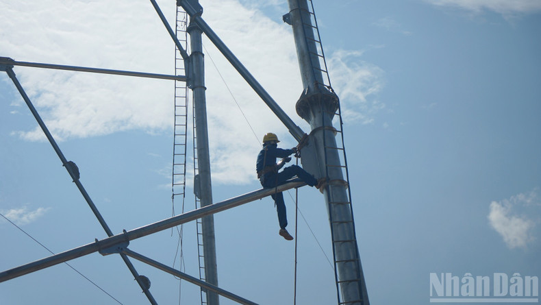Workers erect steel structures at pole VT93, working tens of metres above the ground under intense heat. 3.jpg