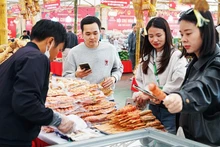 Customers use mobile phones to trace the origin of food products. (Photo: NGUYET ANH)