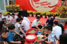 Many Vietnamese and Cambodian staff members of Metfone under the Viettel Military Industry and Telecoms Group (Viettel) take part in wrapping banh chung together during Tet. (Photo: HUY VU)