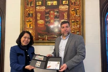 MP Victor Aldaya presents Ambassador Ngo Minh Nguyet with a set of stamps issued by Uruguay's National Post Office in December 2013, commemorating the 20th anniversary of Viet Nam-Uruguay diplomatic relations. (Photo: VNA)