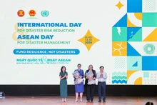 Deputy Minister of Agriculture and Environment Nguyen Hoang Hiep and Pauline Tamesis, UN Resident Coordinator in Viet Nam present flowers to welcome WHO and IOM as new members of the disaster risk reduction partnership. (Photo: VNA)