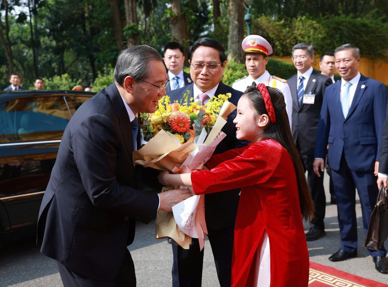 A Hanoi girl presents flowers to welcome Chinese Premier Li Qiang on his official visit to Vietnam. (Photo: VNA)