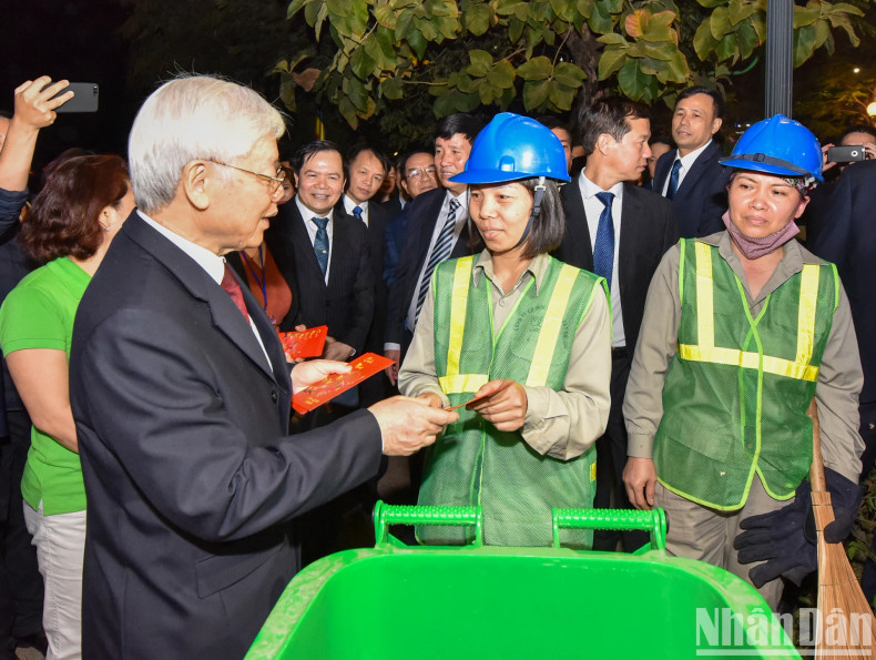 Party General Secretary and President Nguyen Phu Trong extends New Year greetings to workers from the Hanoi Urban Environment Company working around the West Lake on New Year's Eve.