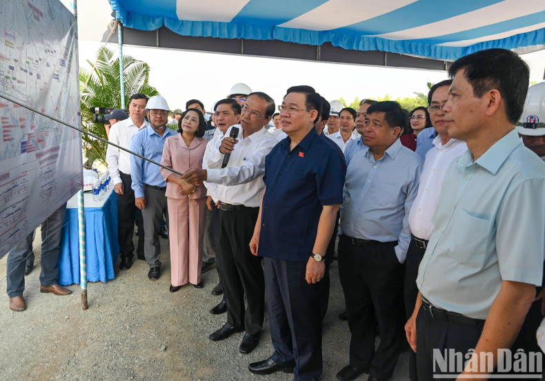 Chairman Vuong Dinh Hue listens to a report on the project's construction progress.