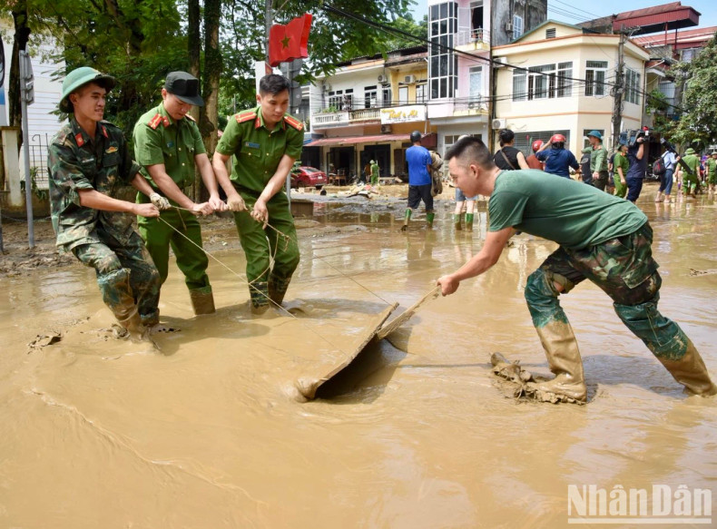 The military and police forces have been working diligently to assist local residents in clearing mud and debris left behind by the storm. (Photo: Tran Hai)