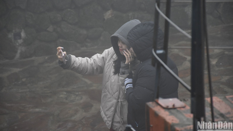 Tourists visit and take photos, capturing beautiful moments at Hai Van Gate under the rain. (Photo: ANH DAO)