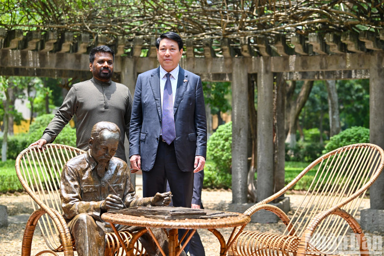 They pose for a photo beside the bronze statue titled “Uncle Ho working in the Presidential Palace's flower garden”.