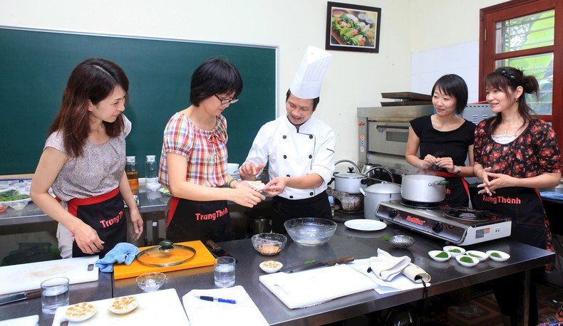 Teachers from Hoa Sua Technical School of Economics and Tourism instruct international visitors in preparing traditional Vietnamese dishes. (Photo: Anh An) Teachers from Hoa Sua Technical School of Economics and Tourism instruct international visitors in preparing traditional Vietnamese dishes. (Photo: Anh An)