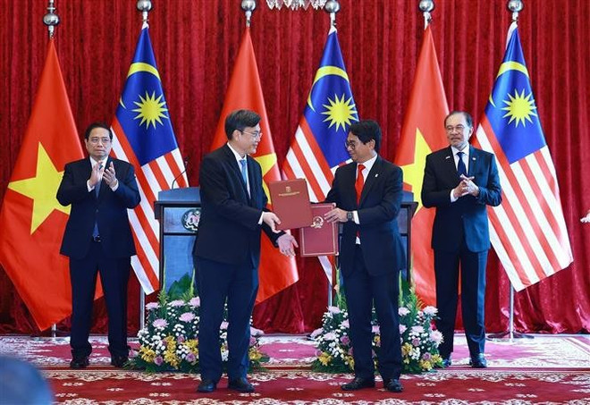 Vietnamese Prime Minister Pham Minh Chinh (L) and his Malaysian counterpart Anwar Ibrahim witness the exchange of a letter of intent on cooperation between the Viet Nam National University, Ho Chi Minh City and the National University of Malaysia. (Photo: VNA)