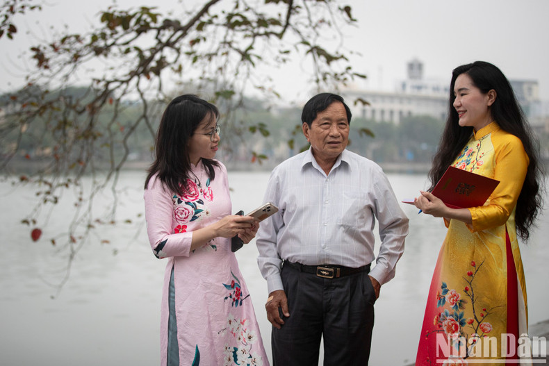 The female reporters interviews a visitor beside Hoan Kiem Lake.