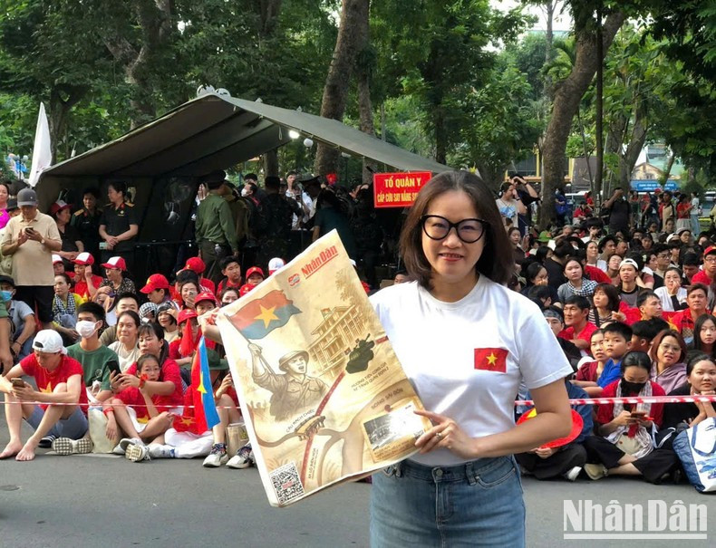 On the morning of April 30, Huong (from District 7 of Ho Chi Minh City), holding a special supplement of Nhan Dan Newspaper, stands by the roadside along Le Lai Street near 23/9 Park,to greet the parade celebrating the 50th anniversary of the Liberation of the South and National Reunification.