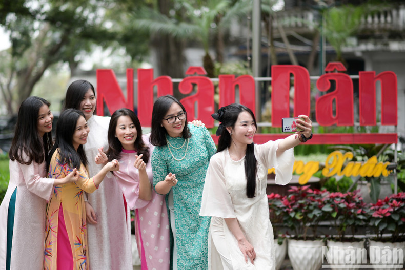 Female reports and employees together capture beautiful moments in the courtyard of Nhan Dan Newspaper.