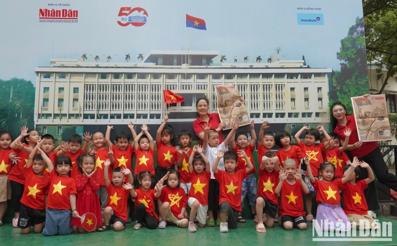 Children from Thang Tam (August) Kindergarten, dressed in red T-shirts with yellow stars, excitedly pose for a photo during their visit to the exhibition.