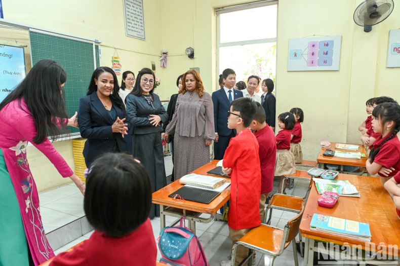 The two ladies visit a classroom and interact warmly with the students. The two ladies visit a classroom and interact warmly with the students.