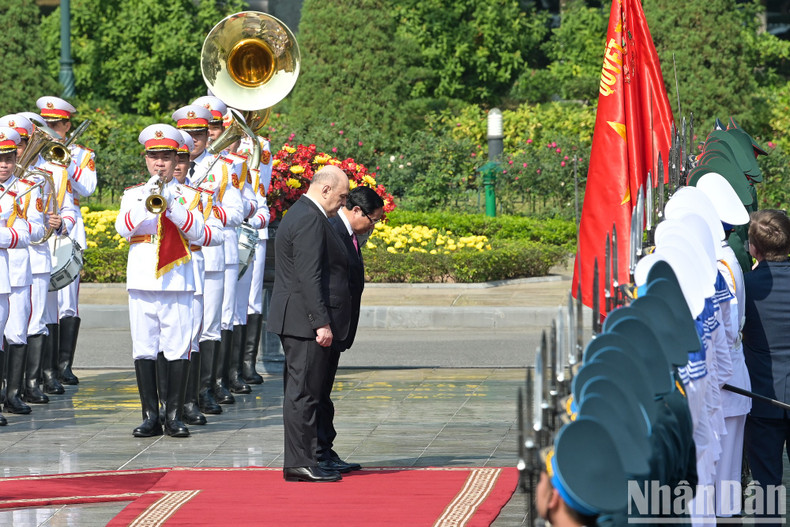 The two Prime Ministers bow to Vietnam’s military victory flag.