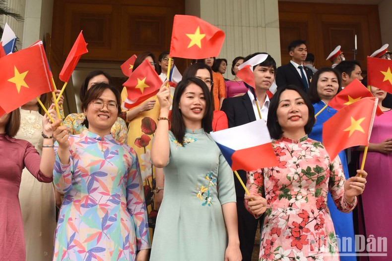 Vietnamese women wave national flags of Vietnam and the Czech Republic.