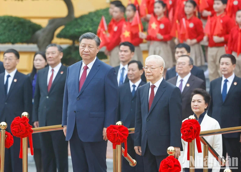 Party General Secretary Nguyen Phu Trong and Chinese Party General Secretary and President Xi Jinping perform the flag salute ceremony.
