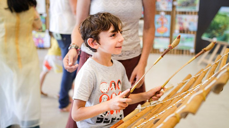A French child excitedly plays the T'rung (bamboo xylophone).