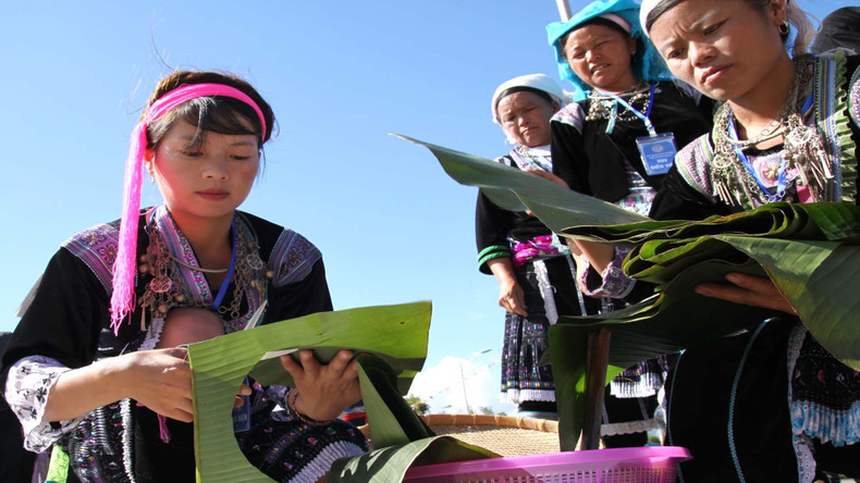The locals prepare banana leaves to wrap the cake.