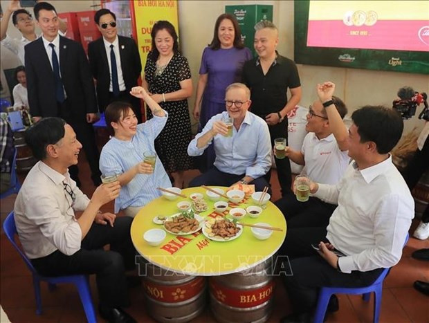 Australian Prime Minister Anthony Albanese drinks "bia hoi" and says cheers with locals in the eatery. (Photo: VNA)