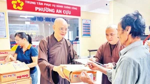 Venerable Thich Hue Phuoc (left) presents support gifts to people affected by flooding in An Cuu Ward, Hue City.