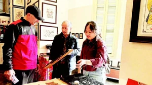 Vo Ca Dao guides foreign visitors in experiencing woodblock printing.