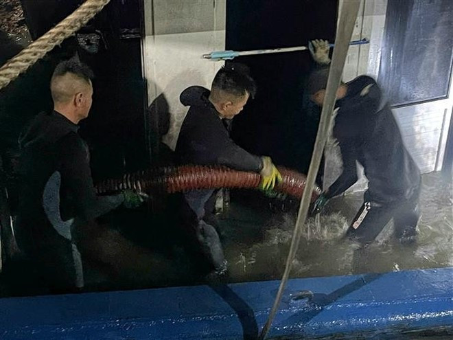 Rescue teams pump water out of the boat before towing it ashore. (Photo: VNA) Rescue teams pump water out of the boat before towing it ashore. (Photo: VNA)
