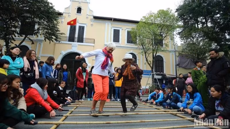 Foreign tourists enjoy a folk cultural activity in Ha Noi (Photo: Nhan dan Newspaper)