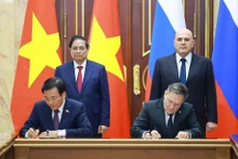 Vietnamese PM Pham Minh Chinh (standing, left) and his Russian counterpart Mikhail Mishustin (standing, right) witness the signing of the agreement between the two governments on cooperation in building a nuclear power plant on the territory of Viet Nam. (Photo: VNA)