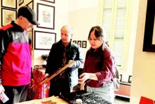 Vo Ca Dao guides foreign visitors in experiencing woodblock printing.