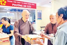 Venerable Thich Hue Phuoc (left) presents support gifts to people affected by flooding in An Cuu Ward, Hue City.