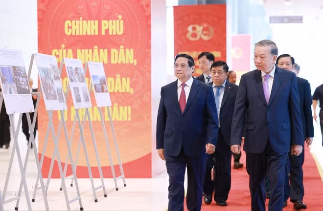 Party General Secretary To Lam (R) and PM Pham Minh Chinh, together with other delegates, visit a photo exhibition on the activities of the Government throughout history. (Photo: VNA)