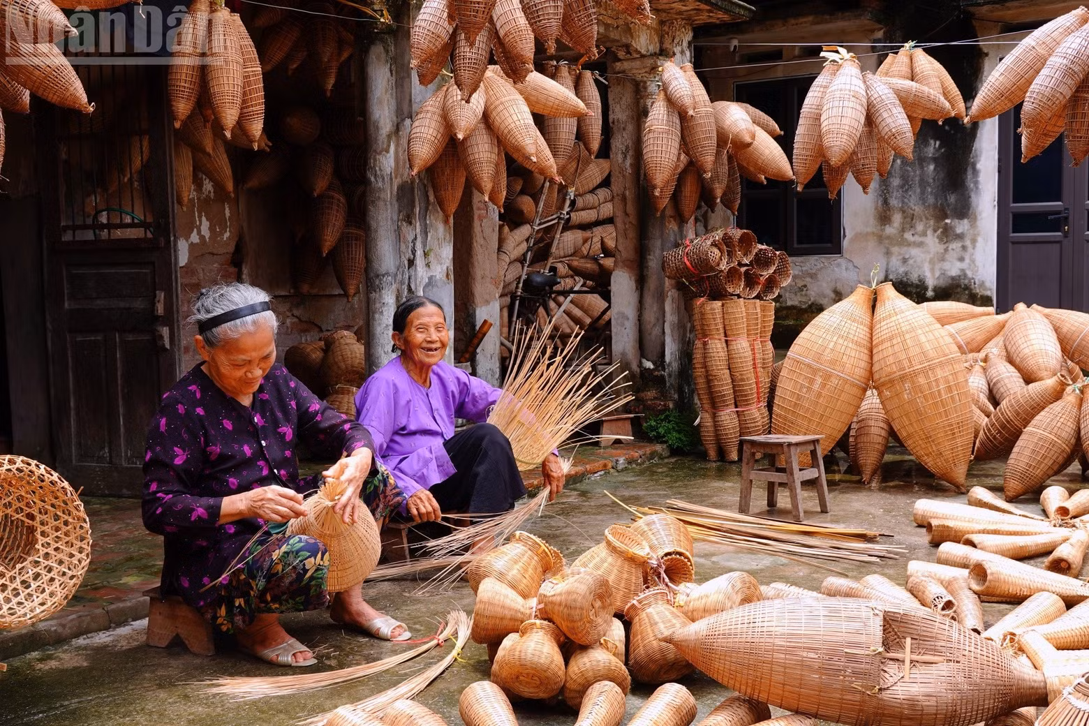 Thuy (left) and Canh happily weave bamboo fish traps outside their home. (Photo: LINH VU)