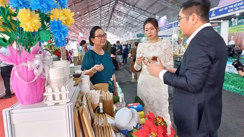 Phan Thi Thuy Phuong (left) introduces biodegradable plastic packaging, straws, and cups to visitors at an exhibition. (Photo supplied by the subject)