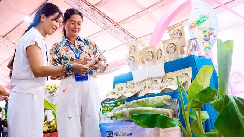 Nguyen Thanh Diem (right) introduces a seeded-banana powder product to visitors at a trade fair. (Photo provided by the subject)