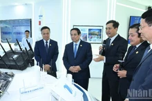 Prime Minister Pham Minh Chinh listens to the leaders of VNPT introduce new technology equipment. (Photo: TRAN HAI).