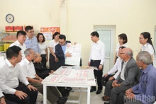 Le Quoc Minh, Editor-in-Chief of Nhan Dan Newspaper, presents the special supplement on the Draft Documents for the 14th National Party Congress to residents at the post office in Da Trach Commune, Hung Yen Province. (Photo: The Dai)