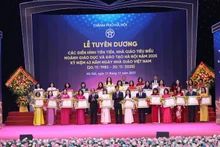 Secretary of Ha Noi Party Committee Nguyen Duy Ngoc and Minister of Education and Training Nguyen Kim Son present the Labour Orders, awarded by the State President, to outstanding collectives and individuals. (Photo: Thanh Tung)