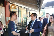 PM Pham Minh Chinh (centre) and his spouse visit the family of Vo Ba Luan - the owner of a restaurant in Nice. (Photo: VNA)