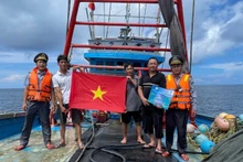 Fishery surveillance officials distribute leaflets on maritime sovereignty and present flags to fishermen at sea.