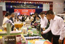 Delegates visit the book display booth of the Vietnamese Embassy in Laos. (Photo: VNA)
