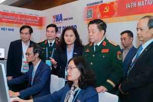 General Nguyen Trong Nghia (standing, front, second from right) visits Viet Nam News Agency reporters covering the 14th National Party Congress on January 20. (Photo: VNA)