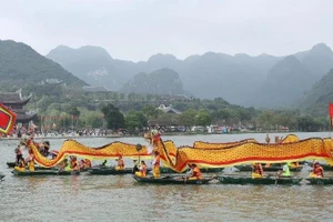 A procession of dragon boats carries sacred water from Tam Chuc Lake to Ngoc Mountain. (Photo: DAO PHUONG)